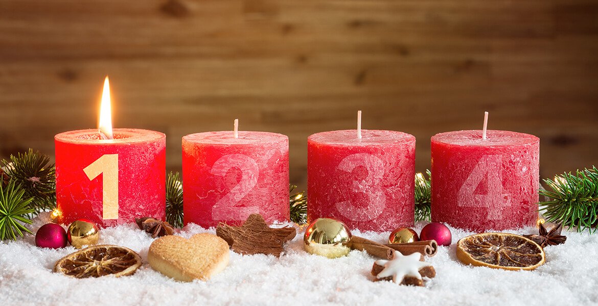 Vier rote nummerierte Adventskerzen mit erster Kerze angezündet und Weihnachtsdekoration in Schnee als Vorlage
