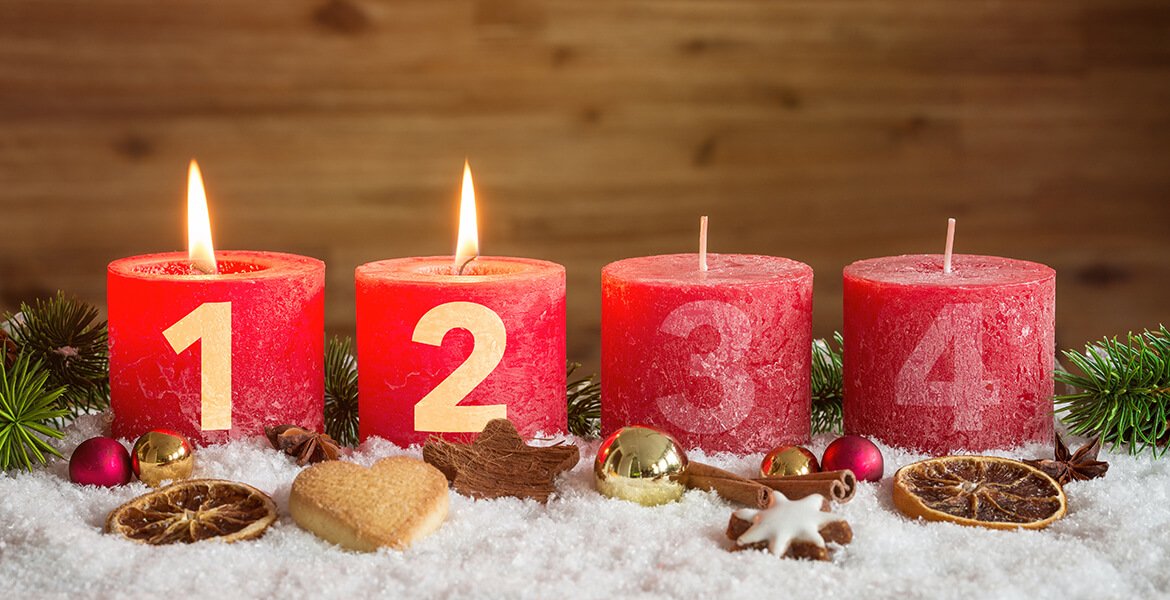 Vier rote nummerierte Adventskerzen mit zweiter Kerze angezündet und Weihnachtsdekoration in Schnee als Vorlage