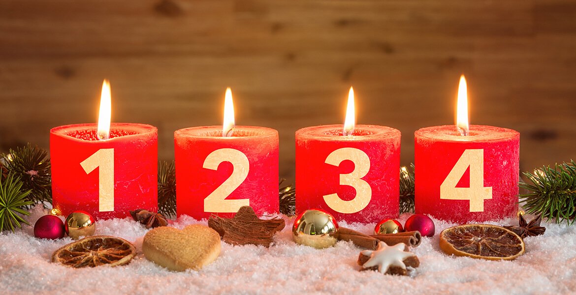 Vier rote nummerierte Adventskerzen mit vierter Kerze angezündet und Weihnachtsdekoration in Schnee als Vorlage